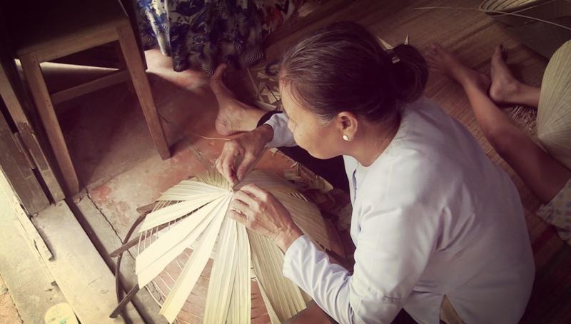 Người dân đang xoay lá trên khuôn nón.